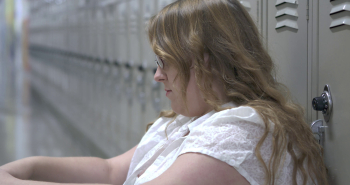 Sad and upset high school student sitting against lockers 4k Stock ...