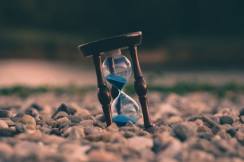 selective focus photo of brown and blue hourglass on stones selective focus photo of brown and blue hourglass on stones