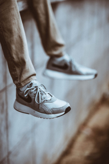 Selective Focus Photo of Person Wearing Gray Nike Shoes Selective Focus Photo of Person Wearing Gray Nike Shoes