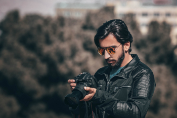 Selective Focus Photography of Man Holding Dslr Camera Selective Focus Photography of Man Holding Dslr Camera
