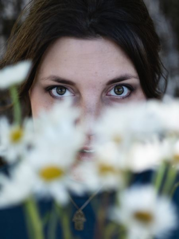 selective focus photography of woman beside daisy flowers