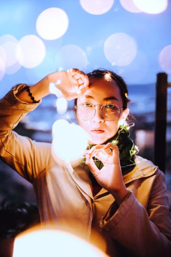 selective focus photography of woman holding string lights