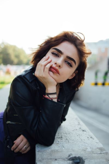 selective focus photography of woman leaning on grey concrete pavement