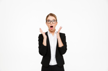 Shocked blonde business woman in eyeglasses holding hands near head Free Photo