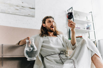 shocked Jesus in crowns of thorns and robe holding jug of water and looking at wine glass in hand at home