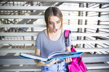 Shocked woman in glasses reading textbook Shocked woman in glasses reading textbook