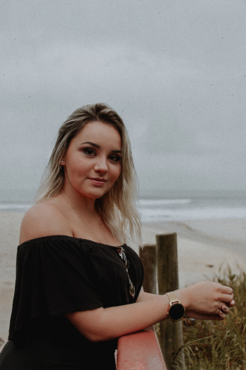 Side View Photo of Standing Woman in Black Tube Top Leaning on Wooden Railing Posing With Beach in the Background