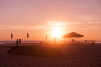 silhouette beach hut near seashore during sunset silhouette beach hut near seashore during sunset