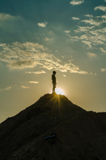 Silhouette of a Man Standing on a Mountain