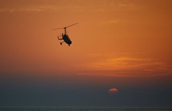 silhouette of helicopter flying during sunset