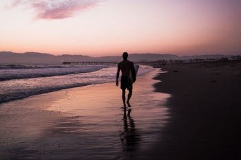 silhouette of man walking along seashore silhouette of man walking along seashore