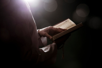 Silhouette of woman reading in quran