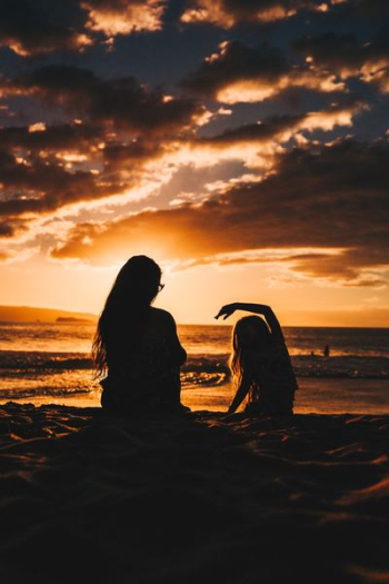 silhouette photo of woman and girl on shoreline silhouette photo of woman and girl on shoreline