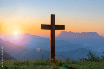 Silhouettes of crucifix symbol with bright sunbeam on the mountain at sunset background