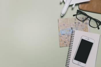 Smartphone and travel supplies on green