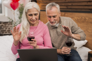 Smiley couple using laptop and drinking wine Free Photo