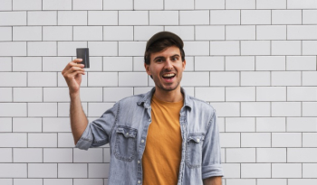 Smiley man holding car on wall background Free Photo