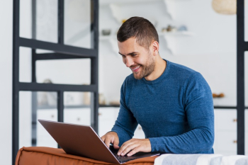 Smiley man working on laptop from home Free Photo