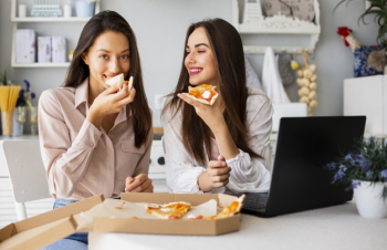 Smiley women eating pizza after working Free Photo