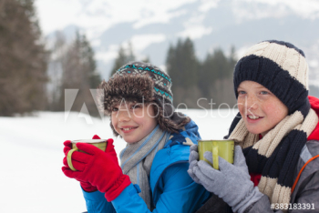 Smiling brothers drinking hot cocoa in snowy field Smiling brothers drinking hot cocoa in snowy field