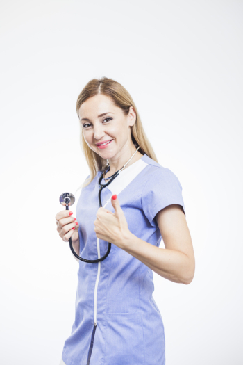 Smiling female dentist gesturing thumbs up on white background