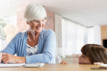 Smiling grandmother and granddaughter at dining table Smiling grandmother and granddaughter at dining table