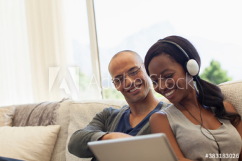 Smiling multiethnic couple using digital tablet on sofa Smiling multiethnic couple using digital tablet on sofa