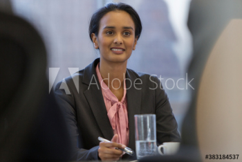 Smiling young businesswoman listening in conference room meeting