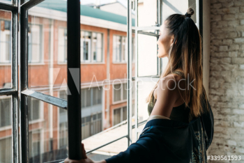 Smiling young woman opening window in morning Smiling young woman opening window in morning