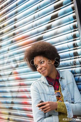 Smiling young woman with afro against graffiti wall Smiling young woman with afro against graffiti wall