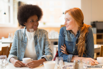 Smiling young women friends drinking coffee in cafe Smiling young women friends drinking coffee in cafe