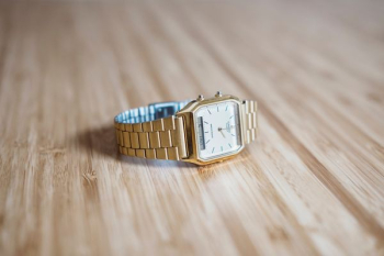 square gold-colored analog watch on brown wooden board square gold-colored analog watch on brown wooden board