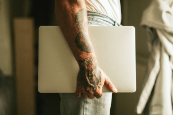 Tattooed alternative man carrying a laptop Tattooed alternative man carrying a laptop