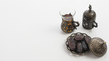 Tea glass and dried juicy date palm fruits or kurma on ramadan food over white background
