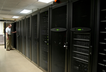 Technician working on racks of 1u and 2u servers in a computer room.