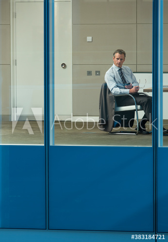 Thoughtful businessman looking out office window Thoughtful businessman looking out office window