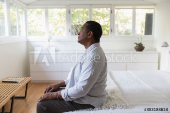 Thoughtful senior man sitting on edge of bed