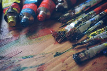 three paint tubes near paint brushes three paint tubes near paint brushes