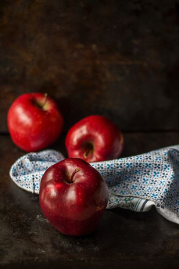 three red apples on brown surface three red apples on brown surface
