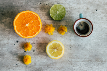 Three Sliced Citrus Fruits Next to a Cup of Coffee