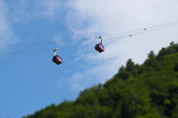 tilt shift photography of two red cable line transports at daytime