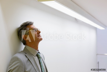 Tired mature corporate businessman leaning against wall Tired mature corporate businessman leaning against wall