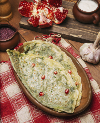 Traditional caucasian vegetable gutab, kutab, gozleme with sumakh, granate seeds and yogurt in wooden plate. Free Photo