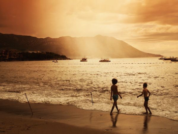 two children walking on beach during sunset two children walking on beach during sunset