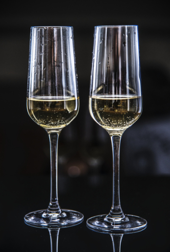 Two Clear Champagne Glasses Filled With Yellow Liquids Two Clear Champagne Glasses Filled With Yellow Liquids