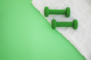 Two dumbbells on white cloth over green background Two dumbbells on white cloth over green background