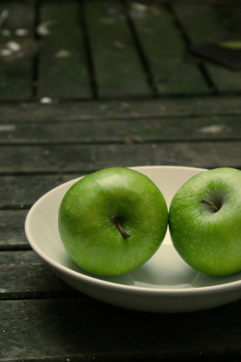two green apples on a white plate two green apples on a white plate