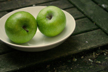 two green apples on a white plate two green apples on a white plate