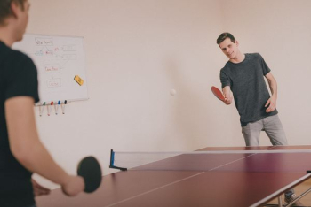 two men playing ping-pong inside room two men playing ping-pong inside room