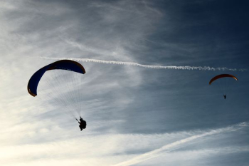 two people riding parachute on clouds during daytime two people riding parachute on clouds during daytime